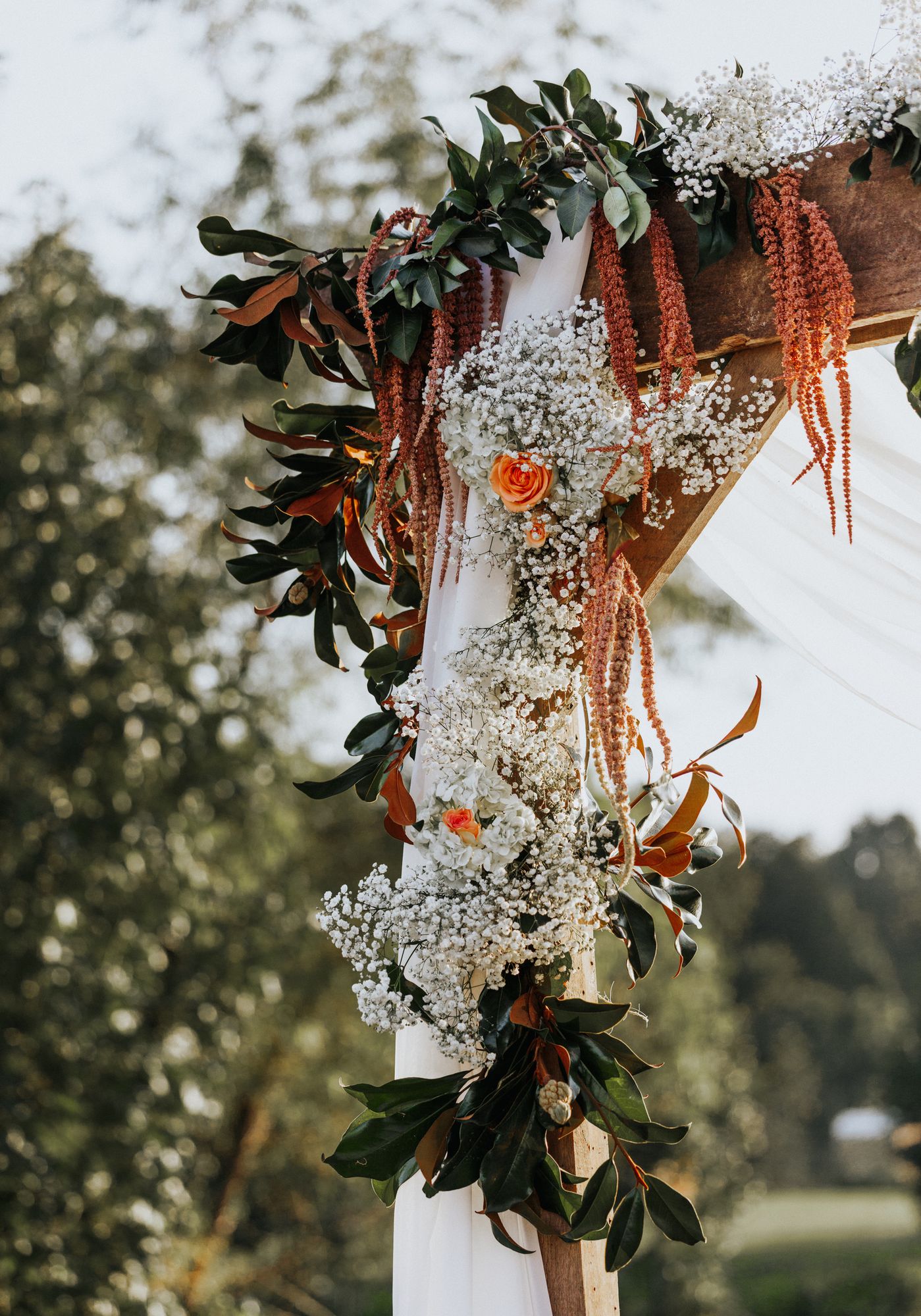 Florals and draped fabric on the wooden ceremony arch