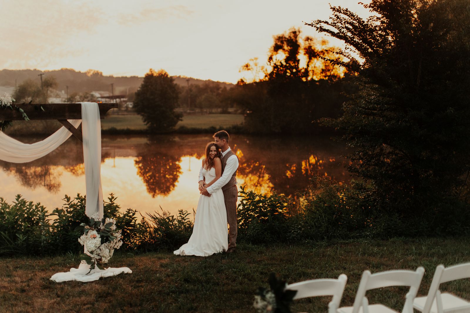 Couple beside the ceremony arch at sunset