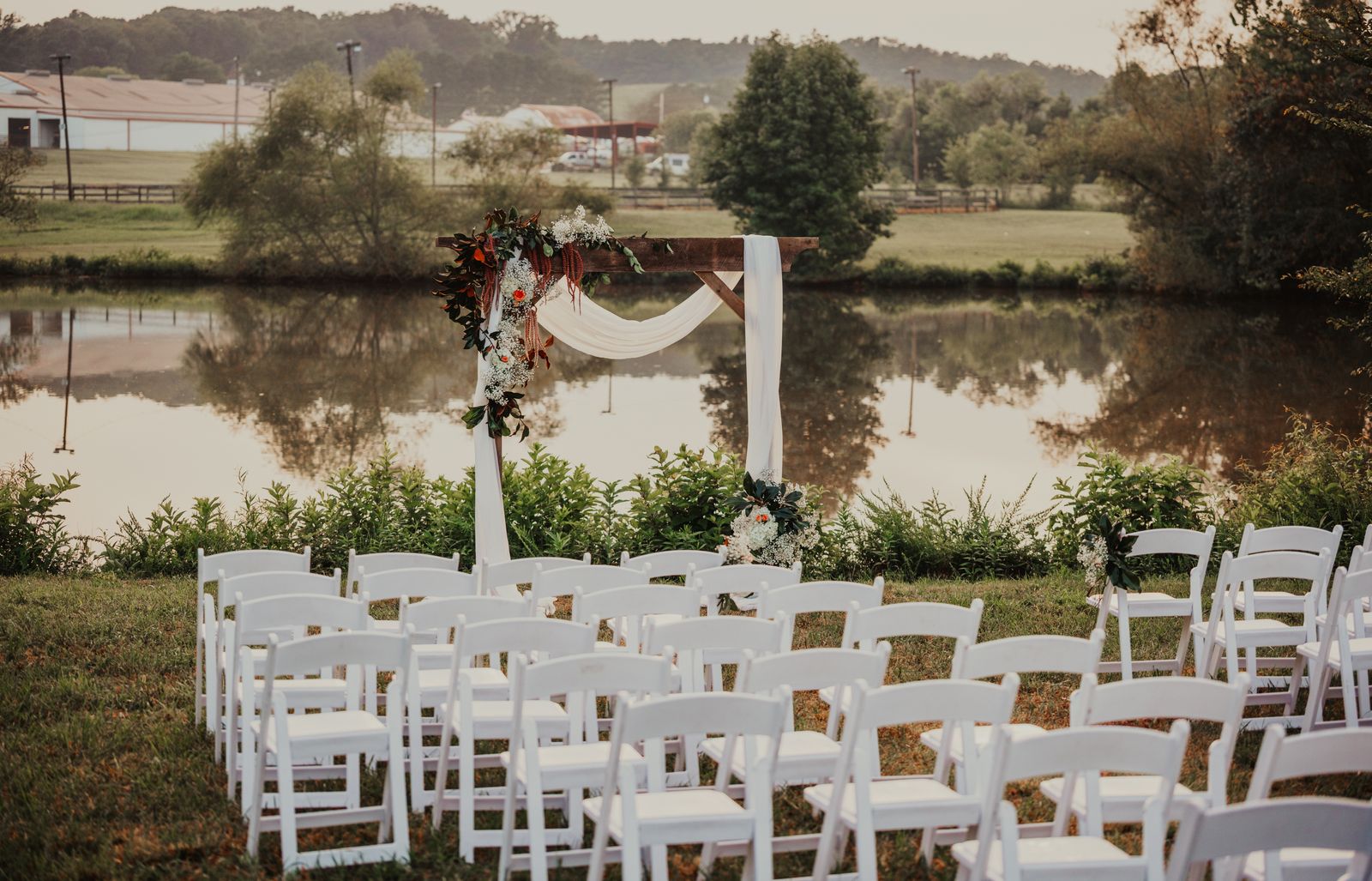 White folding chairs set for a ceremony facing the pond