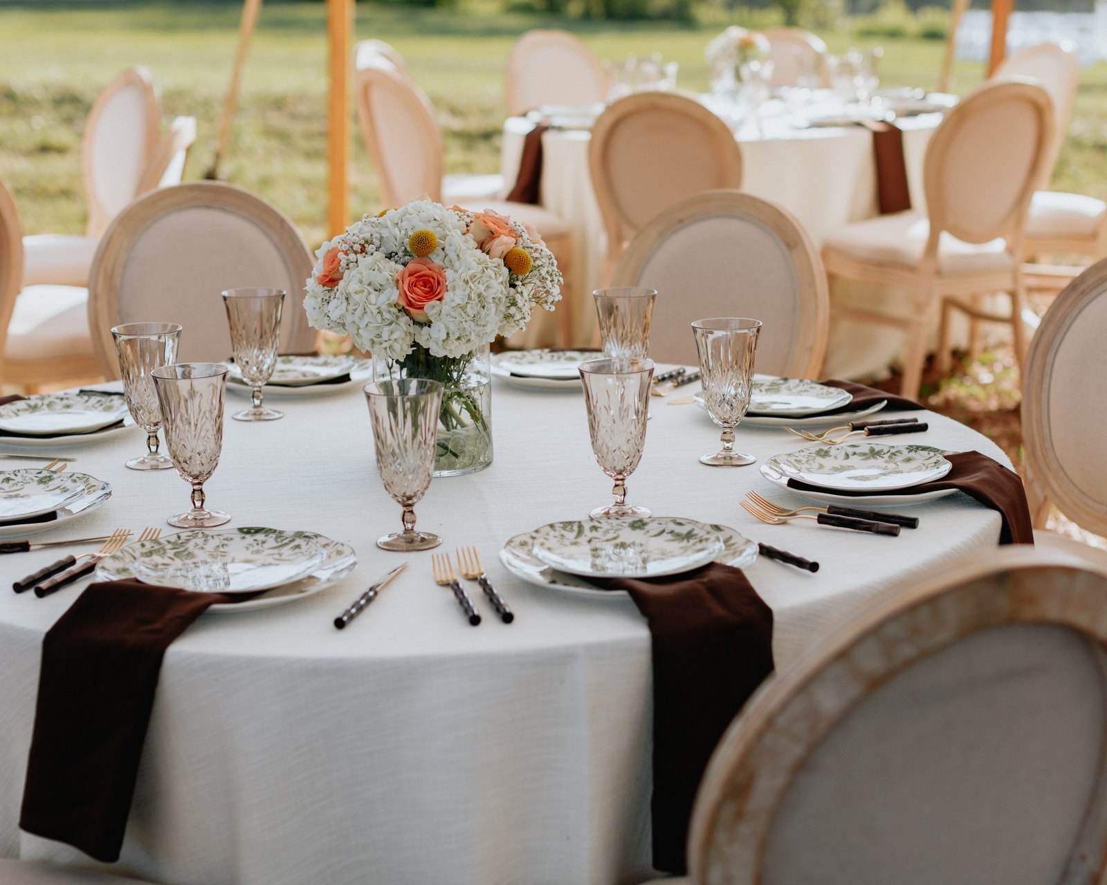 Table set with floral centerpiece, crystal glasses and green floral plates