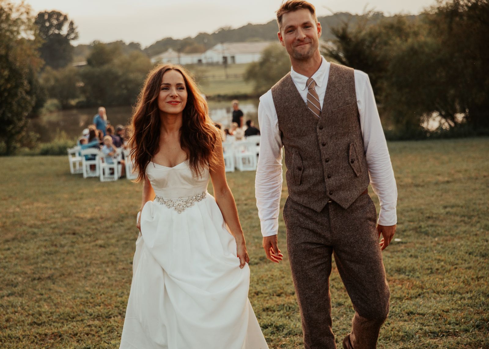 Bride and groom walking through the field after the ceremony